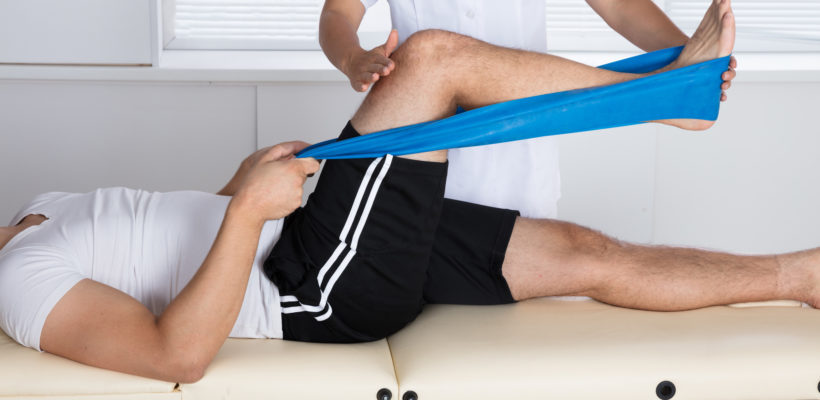 Physiotherapist Helping Patient While Stretching His Leg